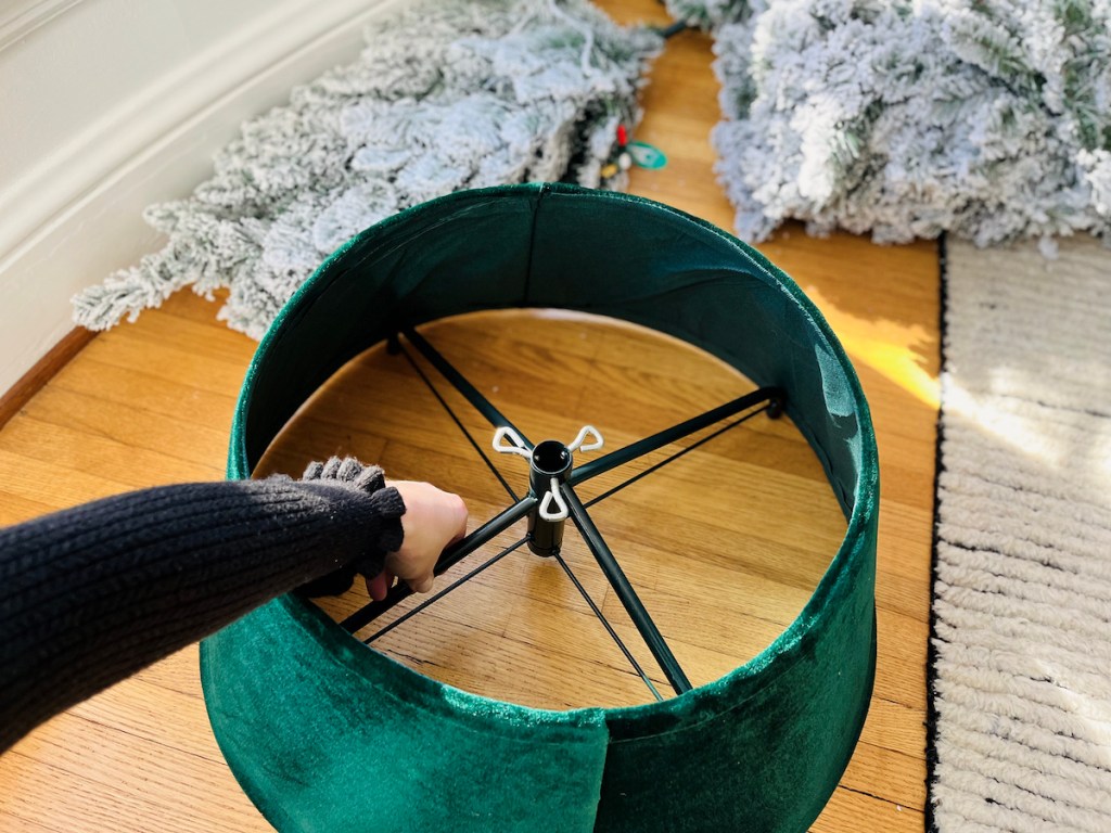 hand holding tree stand inside hunter green velvet tree collar