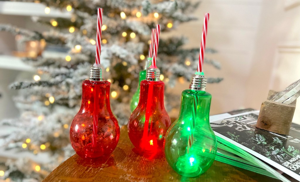 red and green light up bulb cups sitting on table in front of christmas tree