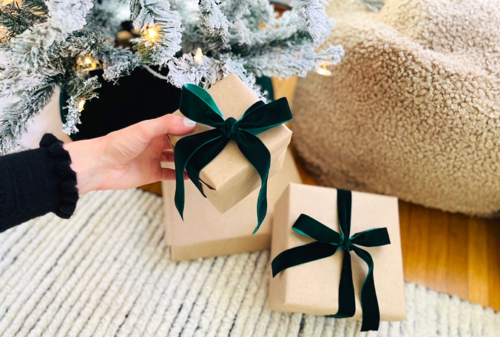 hand holding a wrapped gift with dark hunter green ribbon