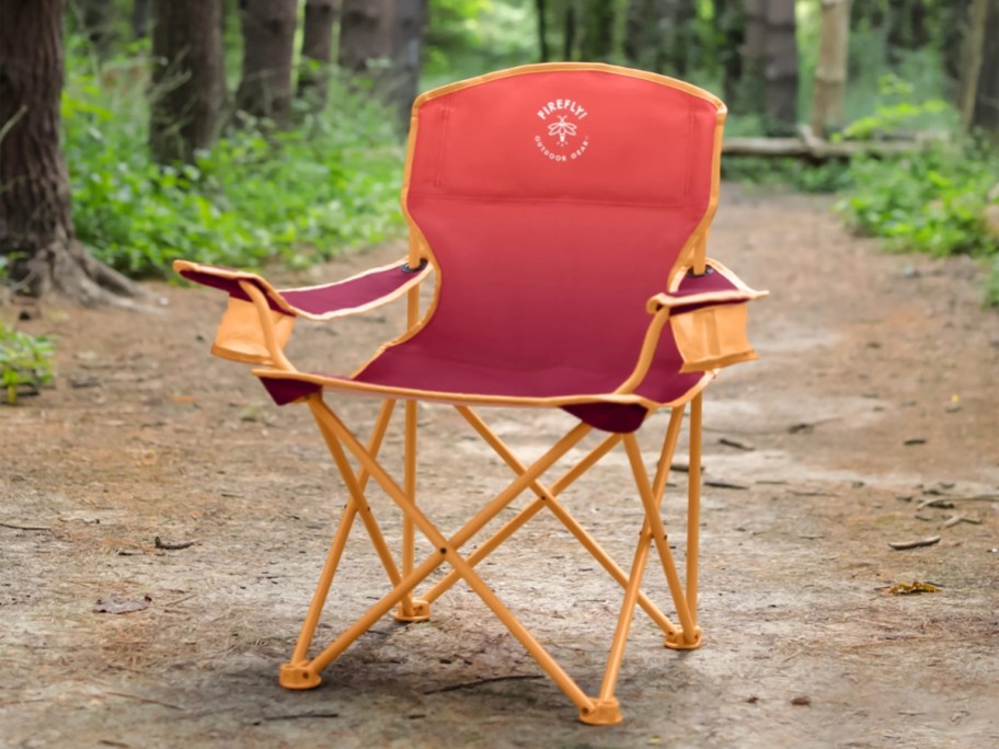 red and orange kid's camping chair sitting on a trail in the woods