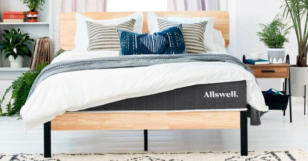 Allswell mattress with white bedding and pillows on wood bedframe in bedroom