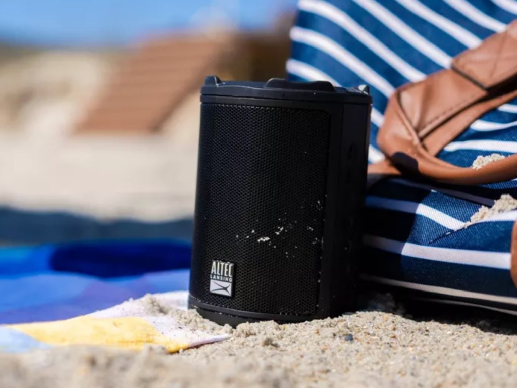 black colored bluetooth speaker sitting on sand at beach