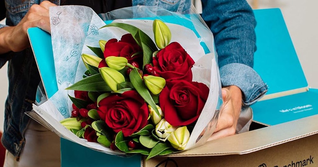 taking bouquet of red roses and lilies out of shipping box
