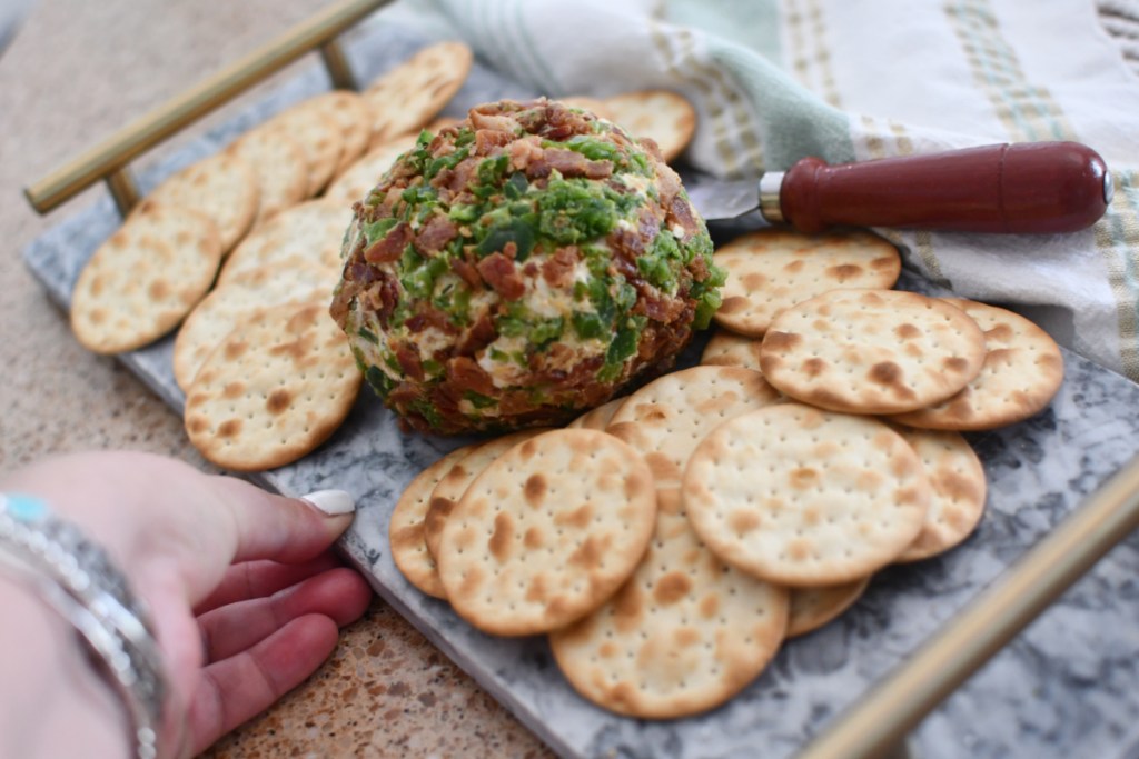 A bacon jalapeno cheese ball served with crackers on a tray