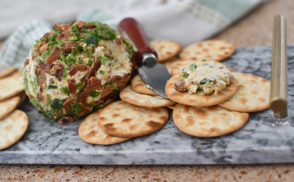 A Bacon Jalapeno Cheese Ball on a serving tray with Crackers