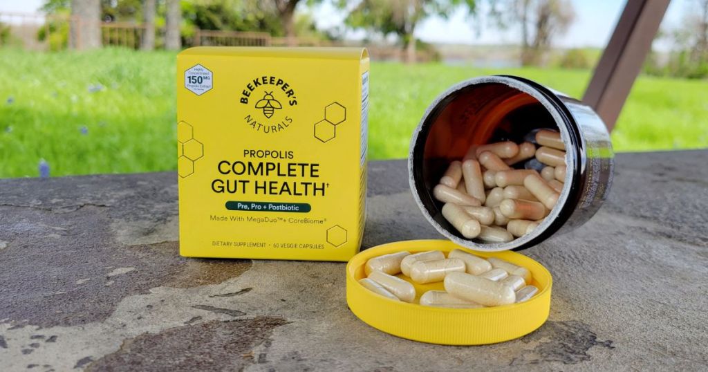 Box of Beekeeper's Naturals Gut Health capsules next to an open container with capsules spilling out