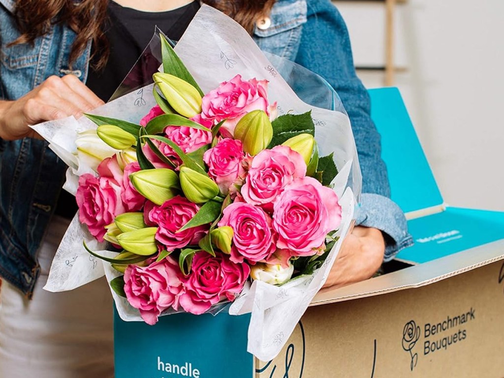 taking bouquet of pink roses and lilies out of shipping box