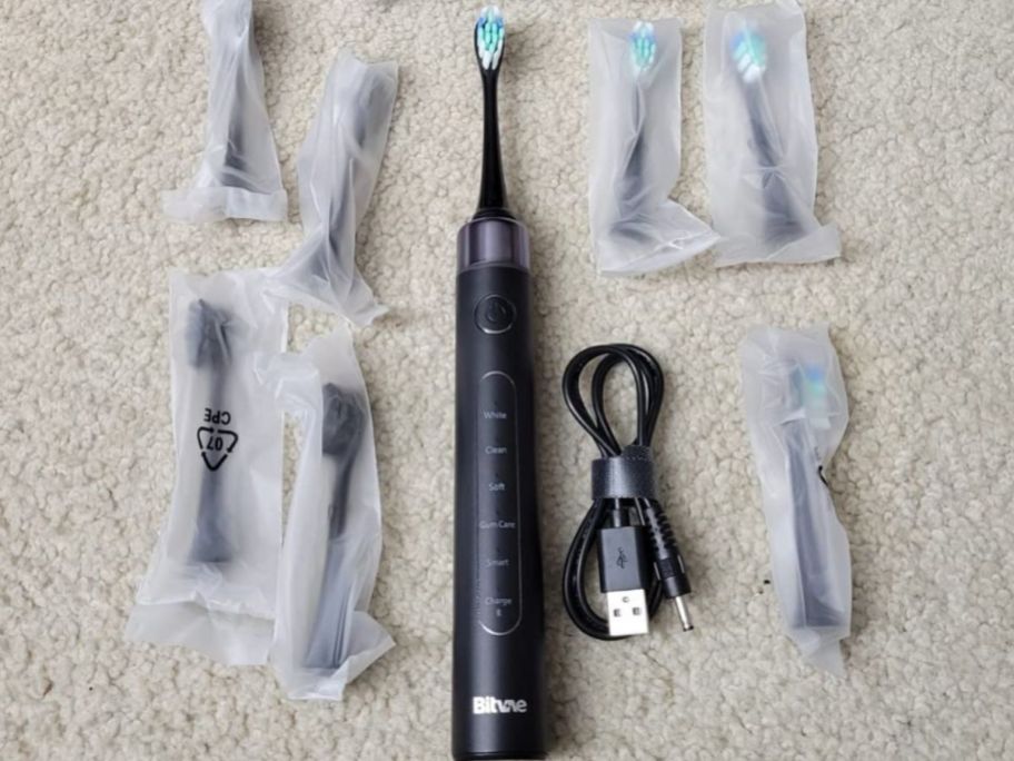 A Bitvae Toothbrush surrounded by brush heads and a charging cable