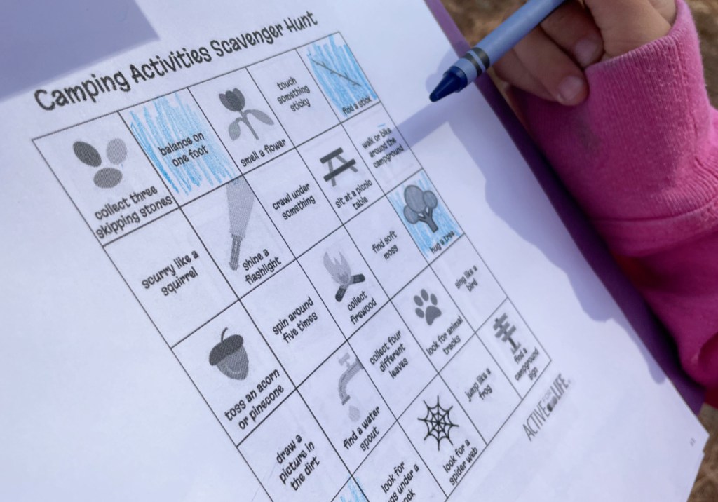 A girl filling in a free printable scavenger hunt to do while camping