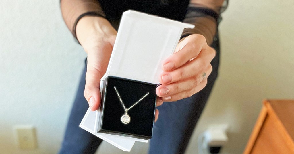 holding up pendant necklace in white box