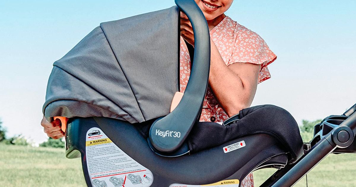 A lady with a Chicco keyfit 30 car seat attaching it to a stroller base 