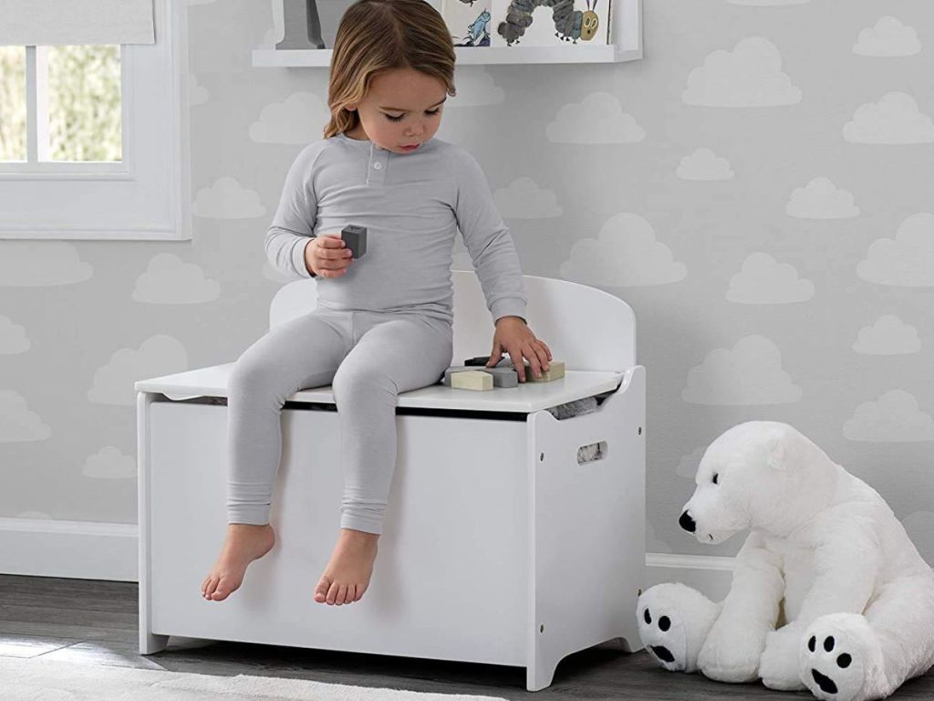 girl sitting on a Delta Toy Box