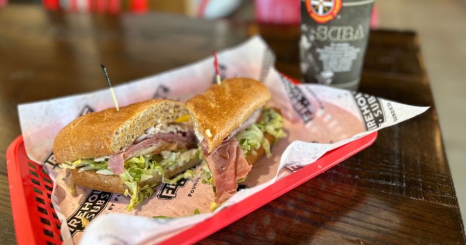 Firehouse Sub cut in half on basket with drink in background