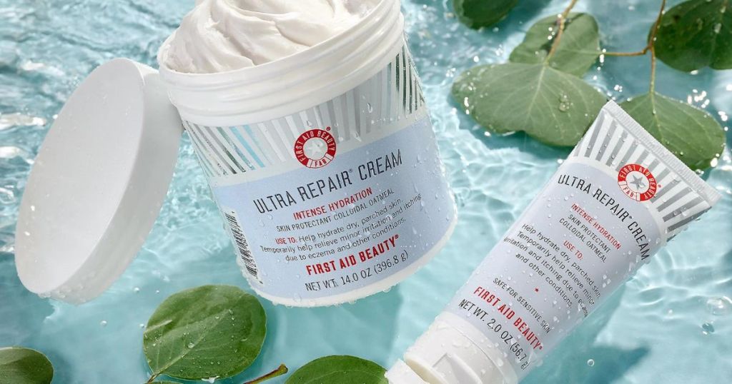 First Aid Beauty Ultra Repair Cream in 14oz jar and 2oz tube floating in water with leaves