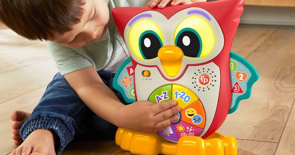 A little boy sitting on the floor playing with Fisher-Price Linkimals Owl