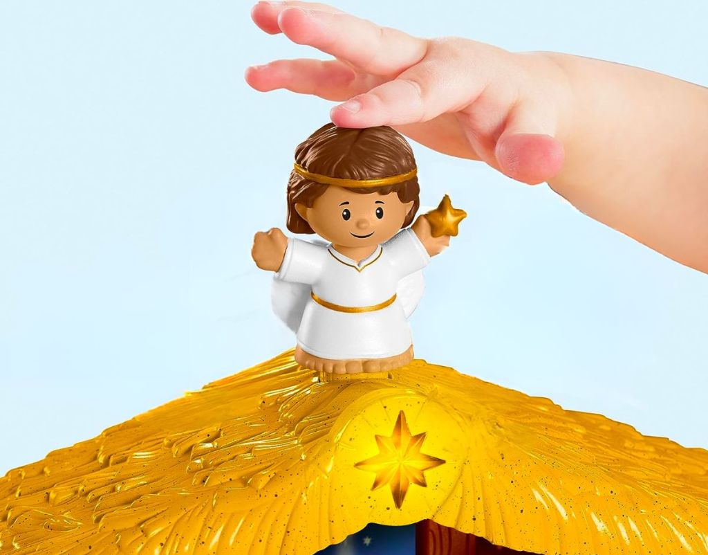 a toddlers hand touching the top of a little people figure on the top of the Fisher-Price Little People Toddler Toy Nativity Set