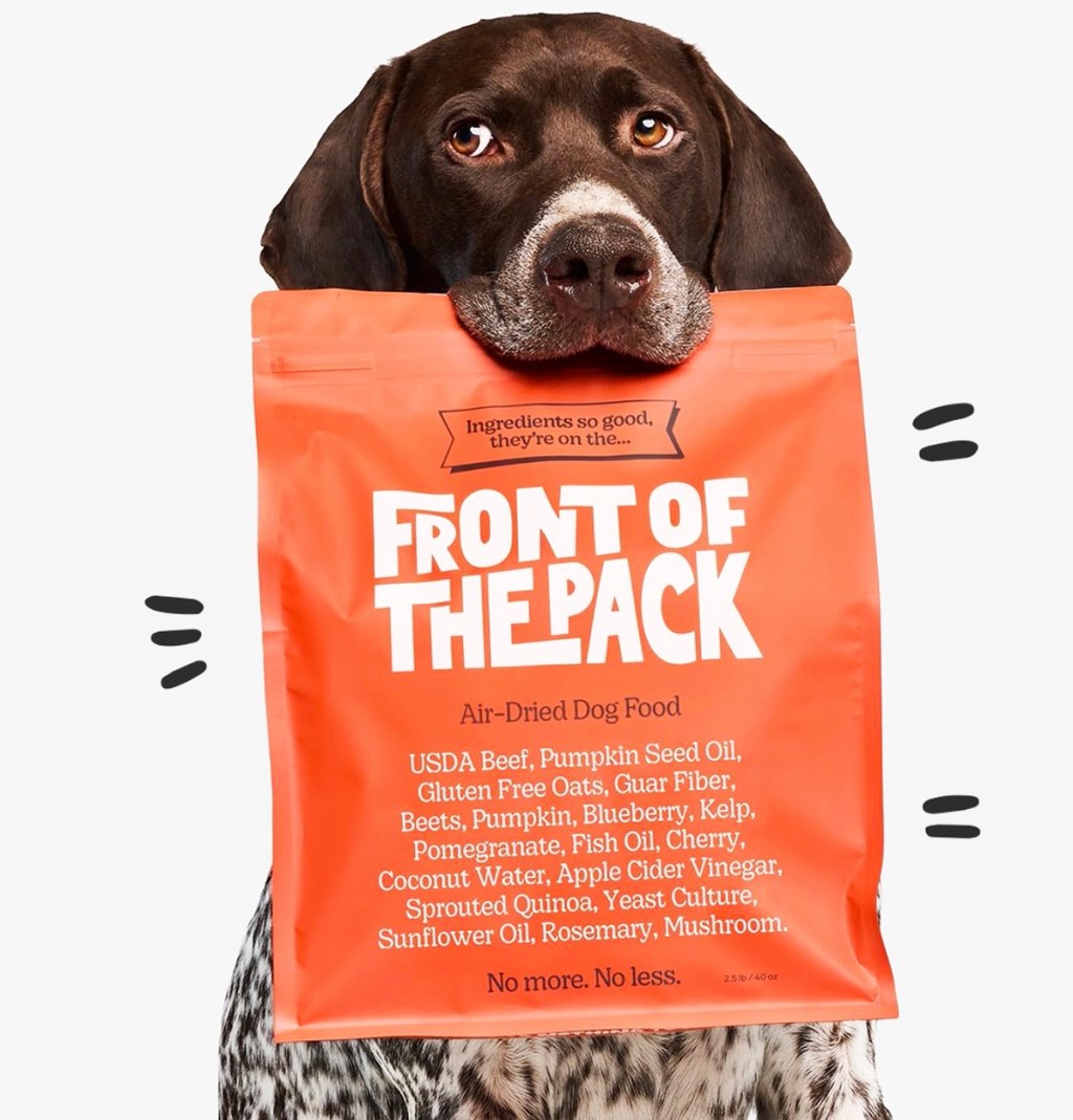 dog holding pack of dog food in mouth