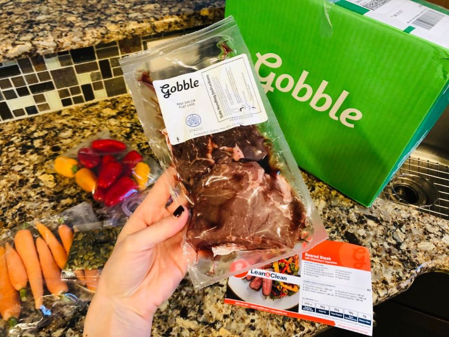 A hand holding Gobble Box veggies and protein