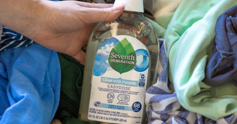 hand holding a bottle of Seventh Generation EasyDose Laundry Detergent Free & Clear 66 Loads in a basket of laundry