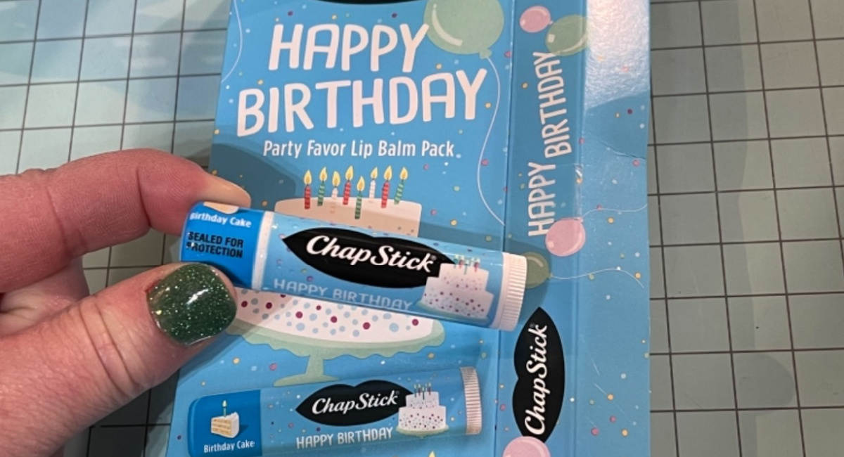Happy Birthday chapstick in woman's hand with 10 pack behind it
