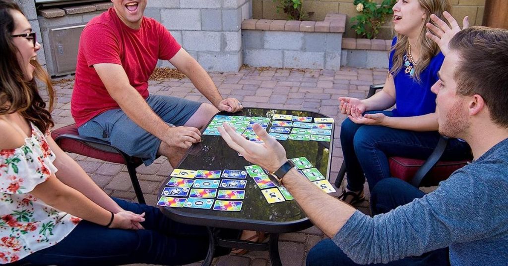 two men and two women playing Skyjo Card game at a patio table outside