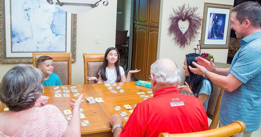 3 generations gathered around the table playing Skyjo card game