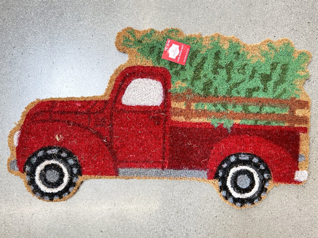 red truck carrying a christmas tree doormat on ground