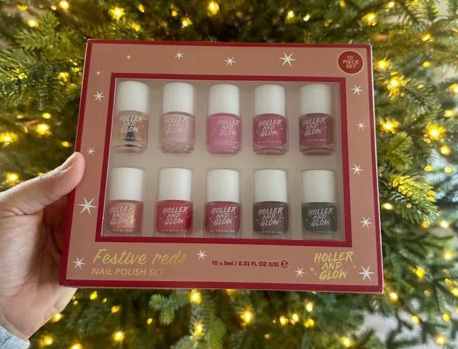 hand holding holler and glow mini nail polish set in front of lit christmas tree