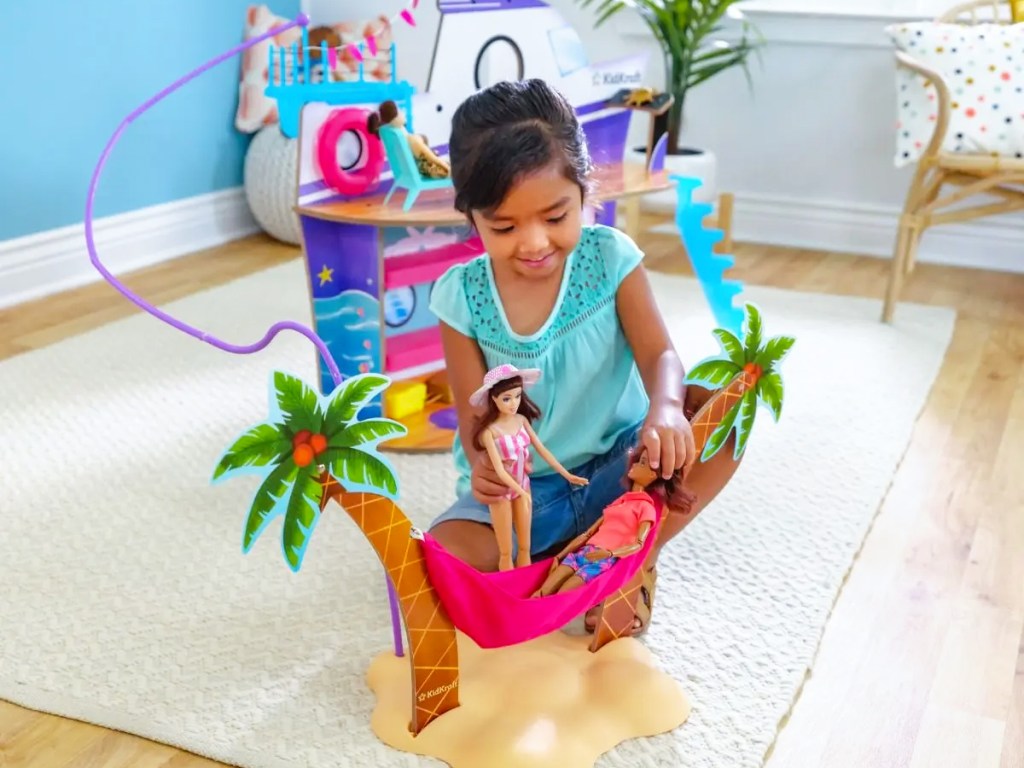 girl playing with dolls in pink hammock on an island playset