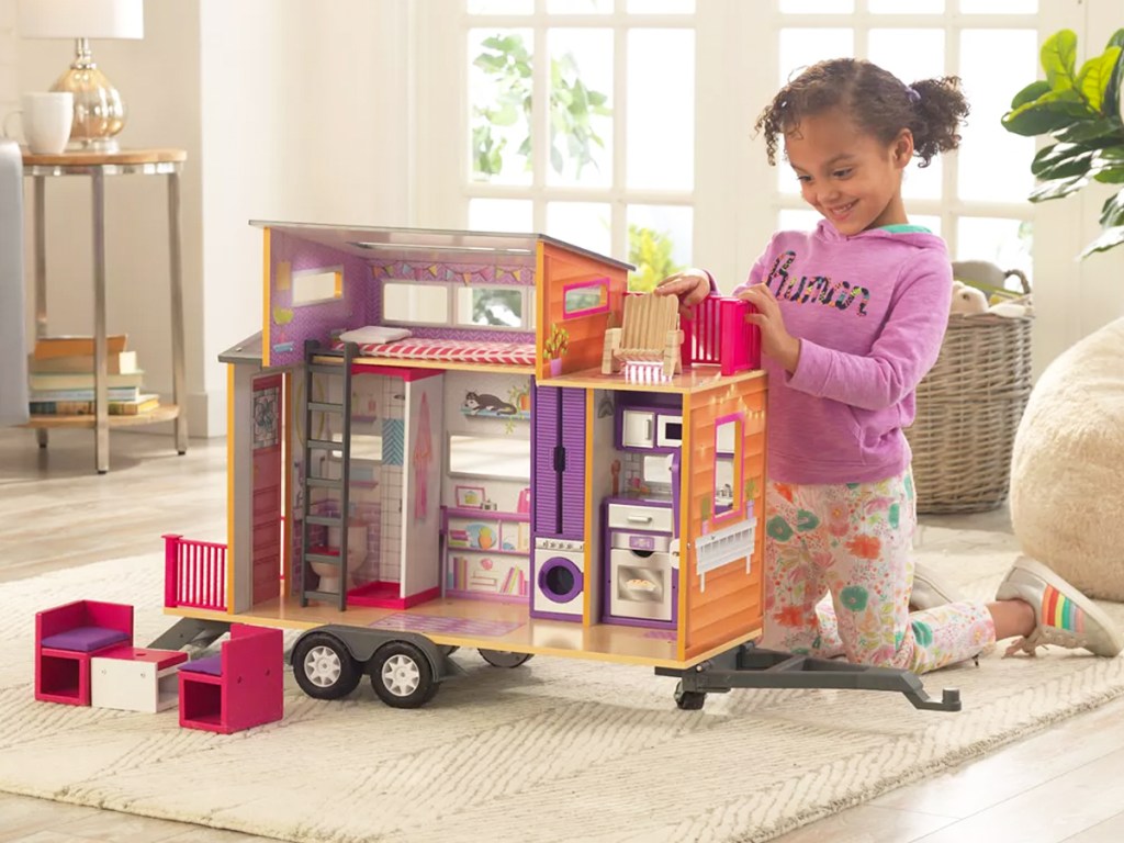 girl playing with small kidkiraft dollhouse on wheels