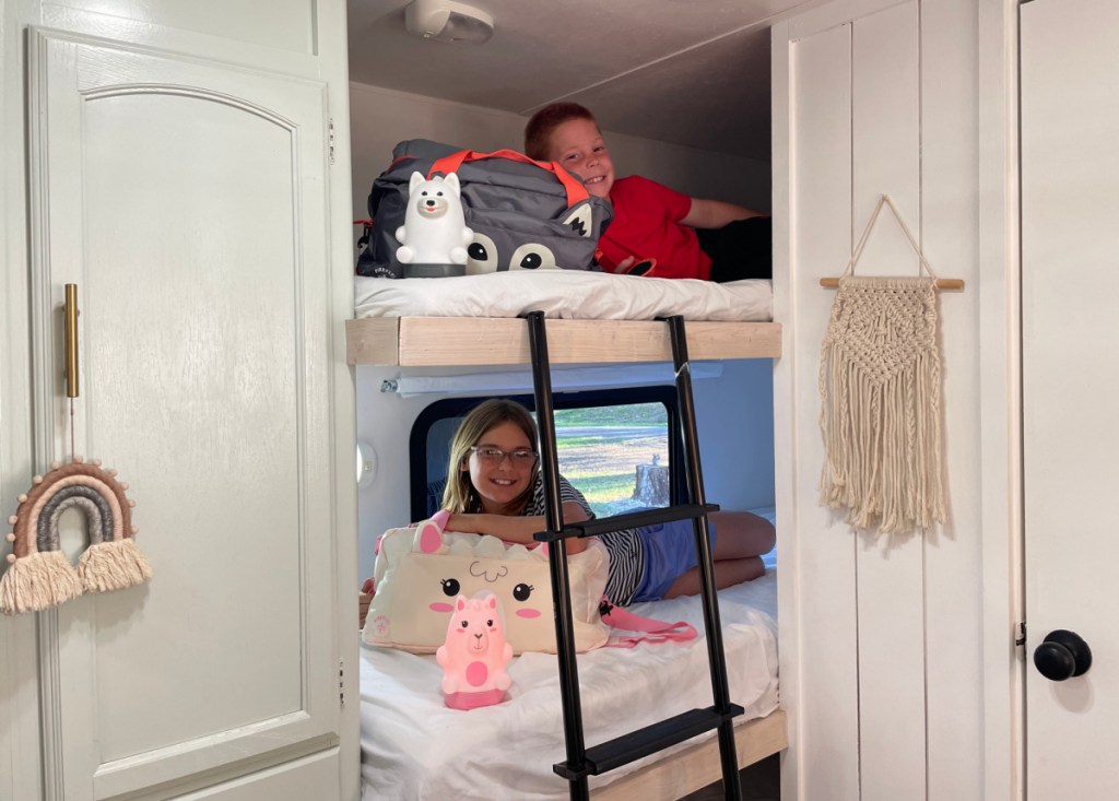 Kids posing on bunk beds with their matching sleeping bags and lanterns from Walmart