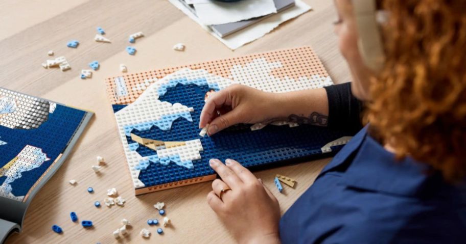 A person constructing a Lego ART Hokusai The Great Wave