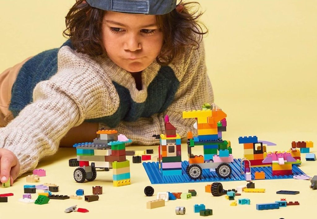 Child building with Legos on a blue base plate