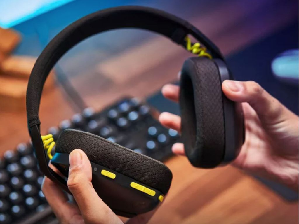 hands holding black headphones with yellow detail