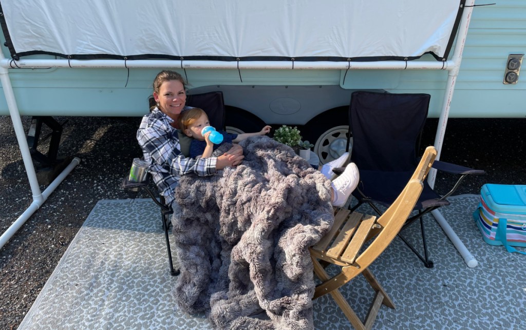 A mom and son lounging outside an RV rental.