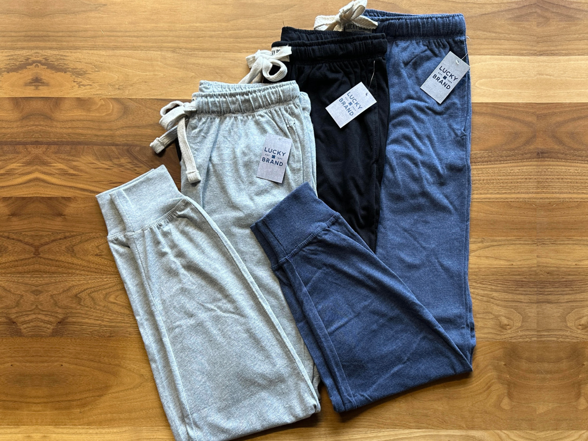 Three pairs of lucky brand joggers stacked on wood floor