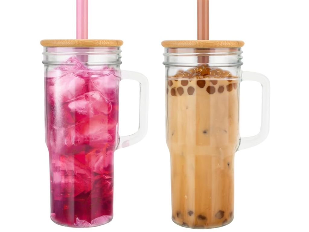2 tumbler style drinking glasses with handles, bamboo lids and straws, one with a fruity drink in it, the other with boba tea in it
