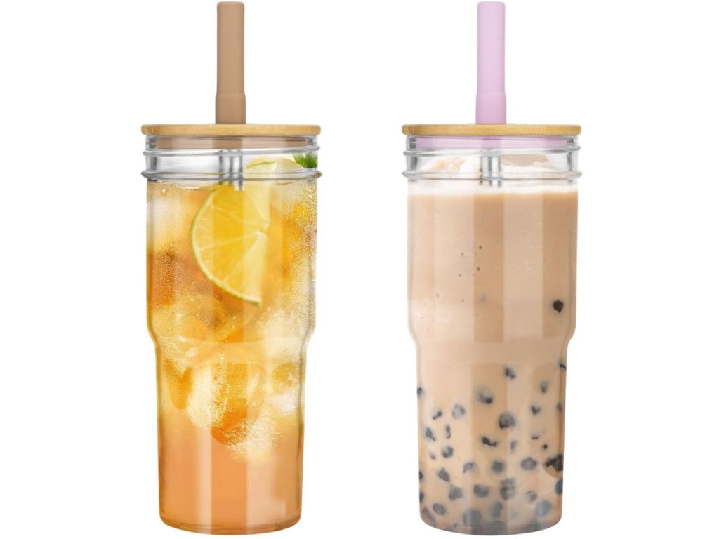 2 tumbler style drinking glasses with bamboo lids and straws, one with a fruity drink in it, the other with boba tea in it