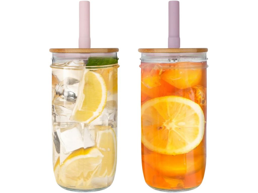 2 mason jar style drinking glasses with bamboo lids and straws with fruity drinks inside