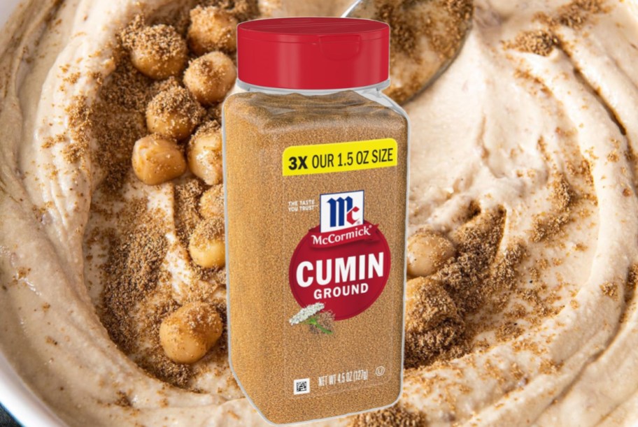 Mccormick ground cumin bottle displayed with hummus behind it