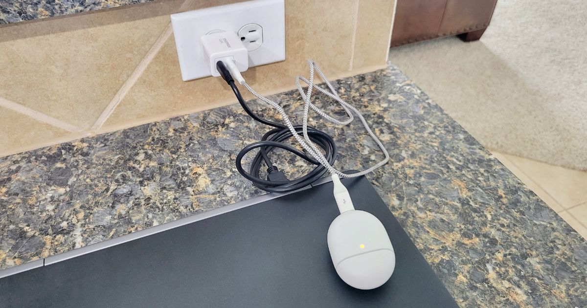 Momax charger plugged into laptop and earbuds case 