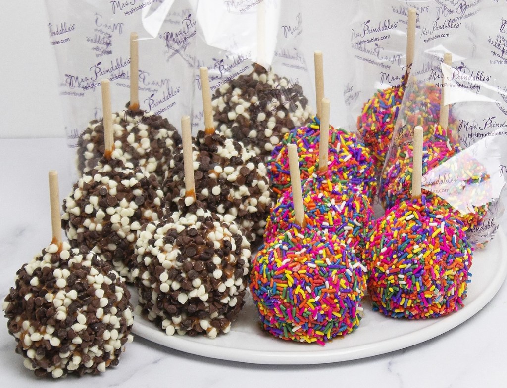 Caramel apples with sprinkles and chocolate pieces on them on a plate