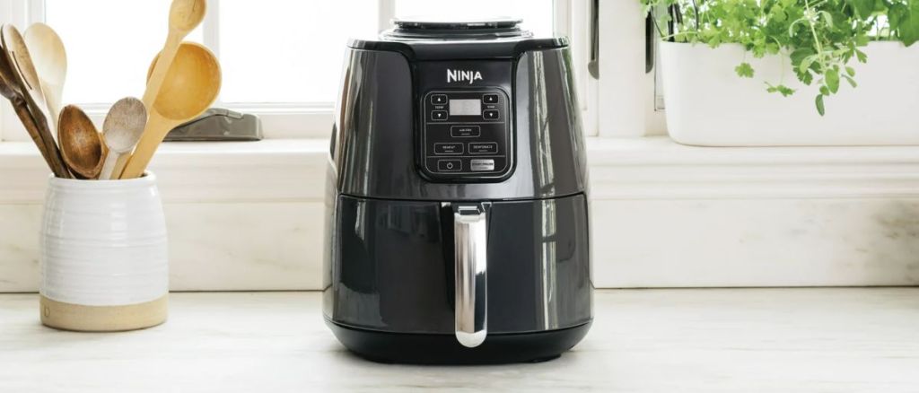 Ninja 4qt air fryer with reheat and dehydrate sitting on a kitchen counter by a sunny window