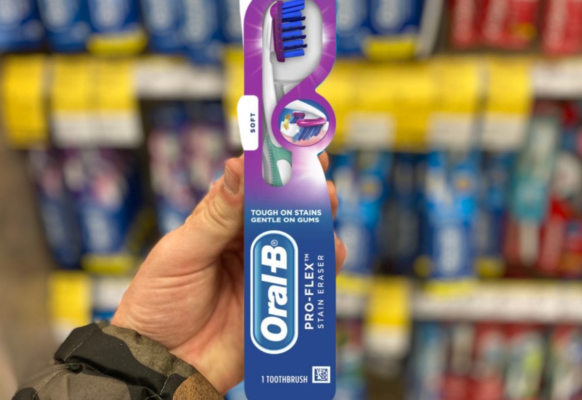 hand holding up an oral B manual toothbrush in the package