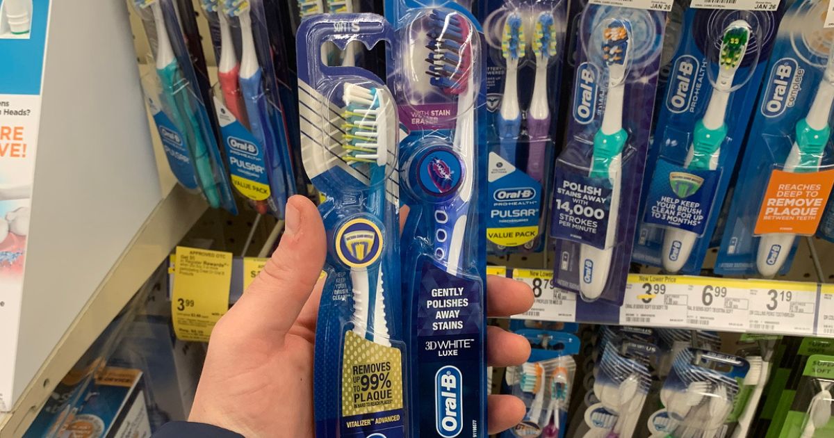 hand holding two oral b toothbrushes in the package 