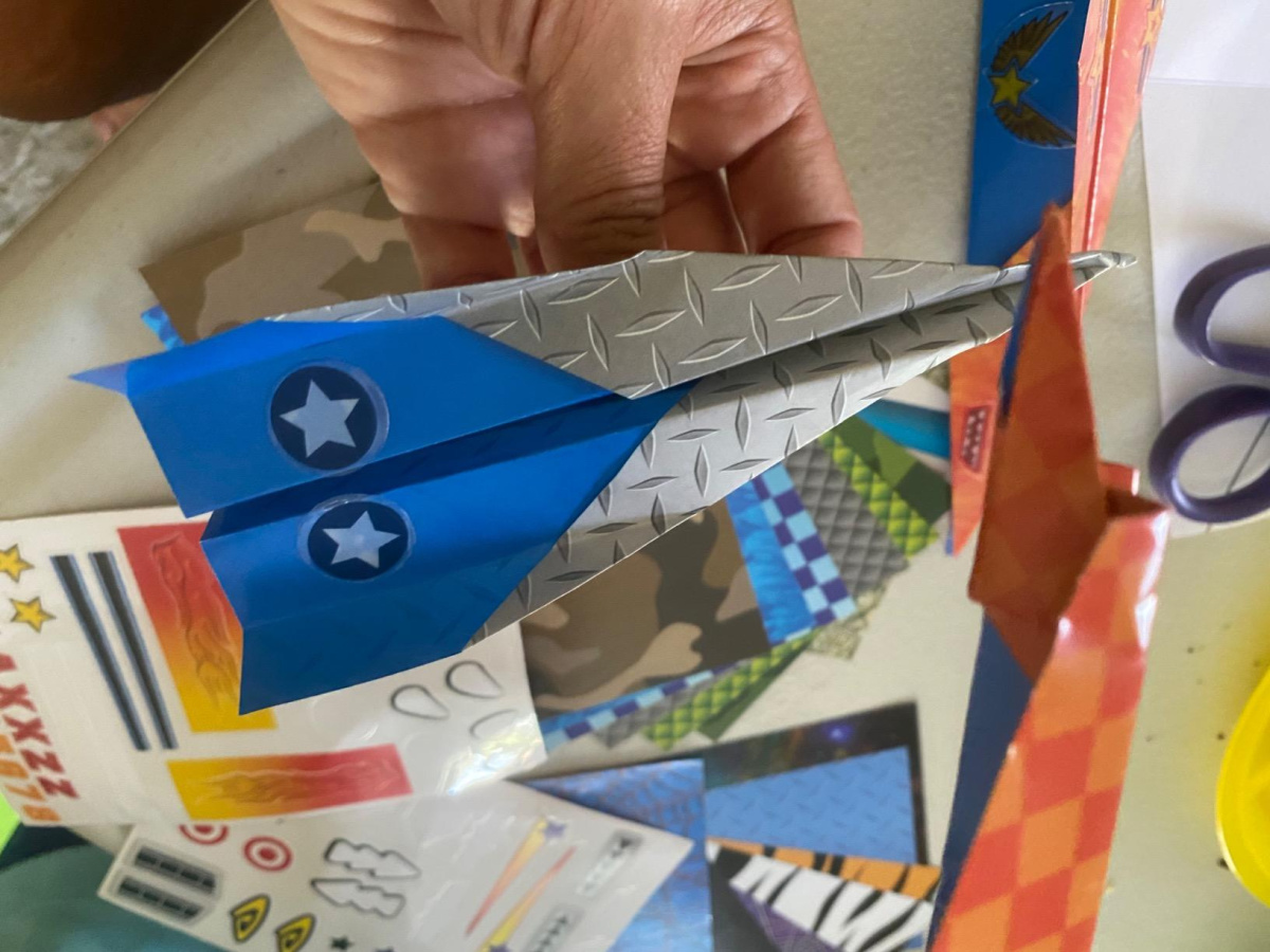 hand holding a Paper Airplane made from a stocking stuffer Kit for kids