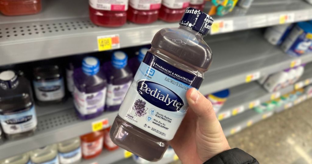 A hand holding a bottle of grape pedialyte