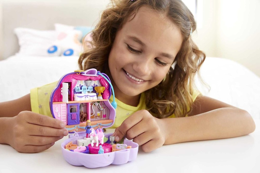 young girl playing with a polly pocket pony compact