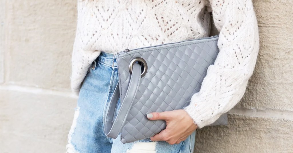 woman holding large grey quilted clutch