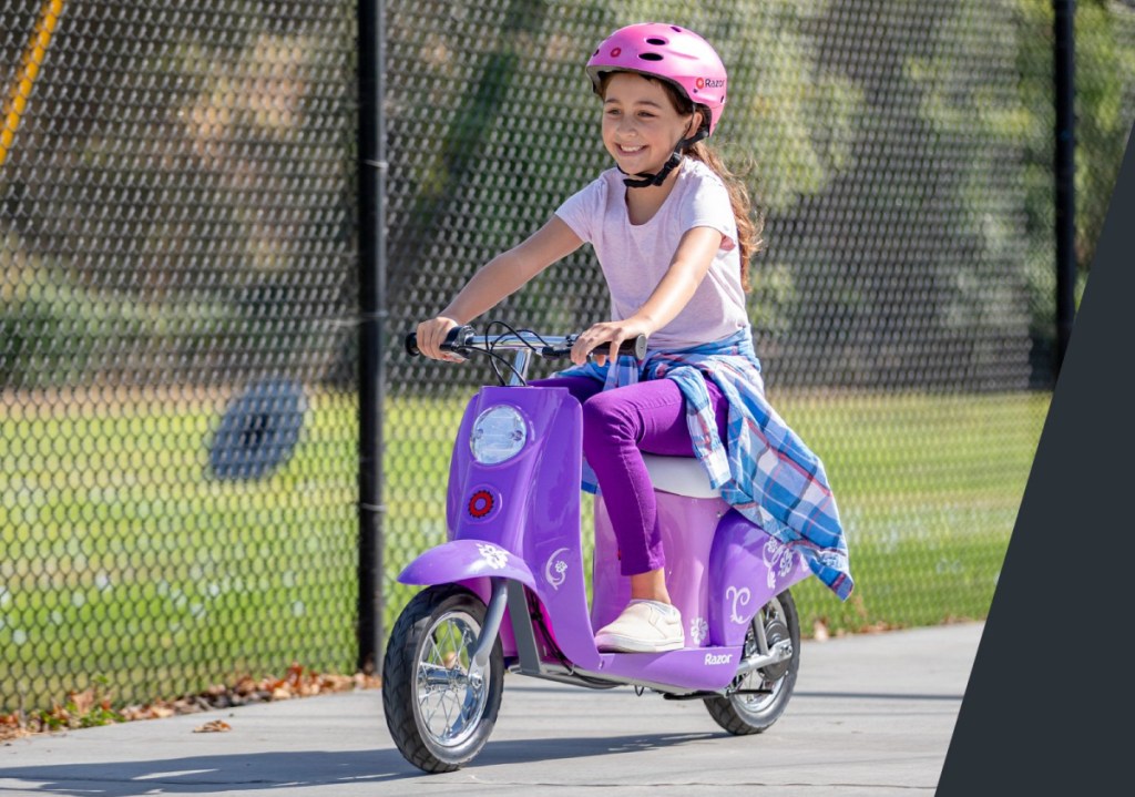 girl riding a purple razor electric scooter wearing a pink helmet